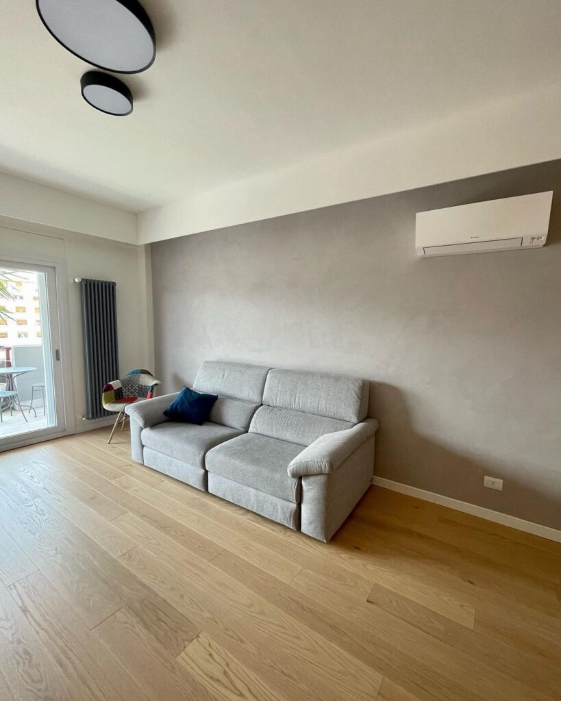 Living di Casa R.M. illuminato da plafoniere Yomo dimmerabili a luce calda, con arredamento minimalista e dettagli in legno.